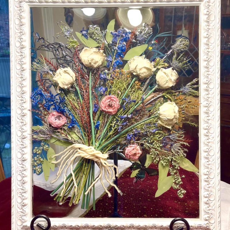 A painting of flowers in a glass case