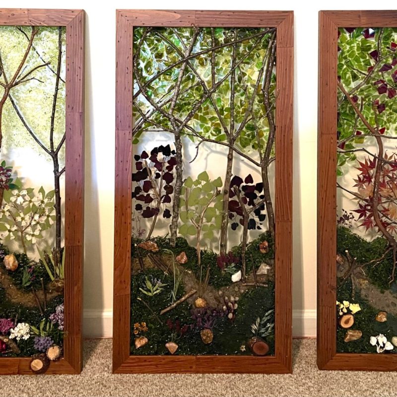 Three framed pictures of trees and flowers on a wall.